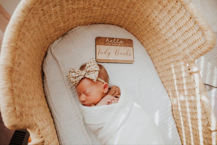 a baby is sleeping in a wicker crib with a name tag on it