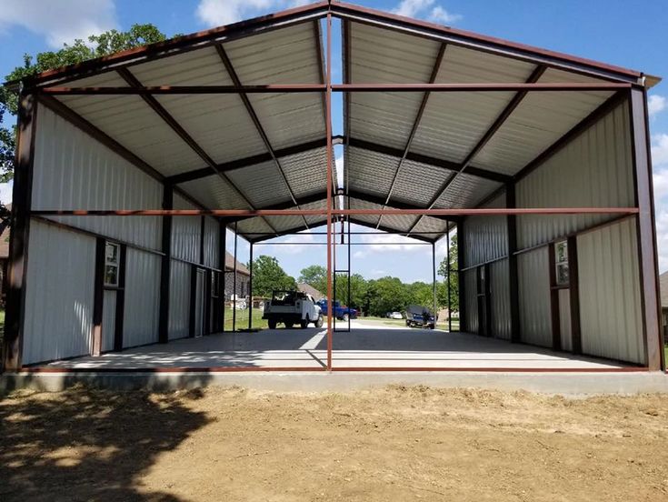 a large metal building sitting on top of a dirt field next to a parking lot