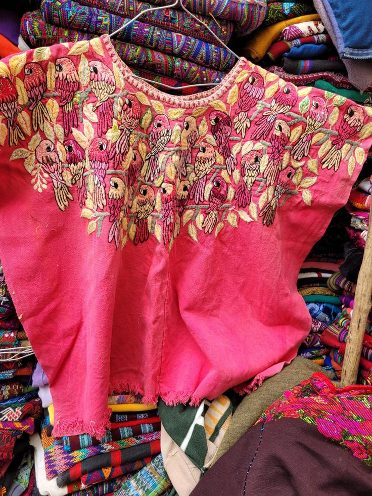 a pink top with flowers on it sitting next to other fabrics