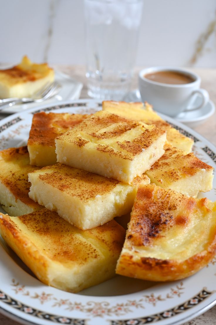 some food is sitting on a plate near a cup and saucer with a spoon