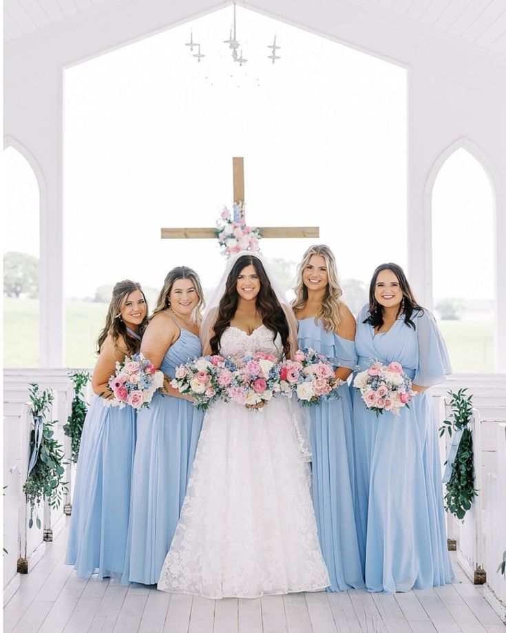 a group of women standing next to each other in front of a cross