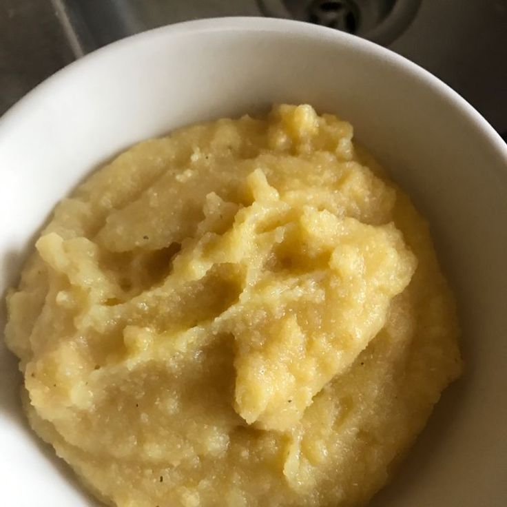 a white bowl filled with mashed potatoes on top of a stove