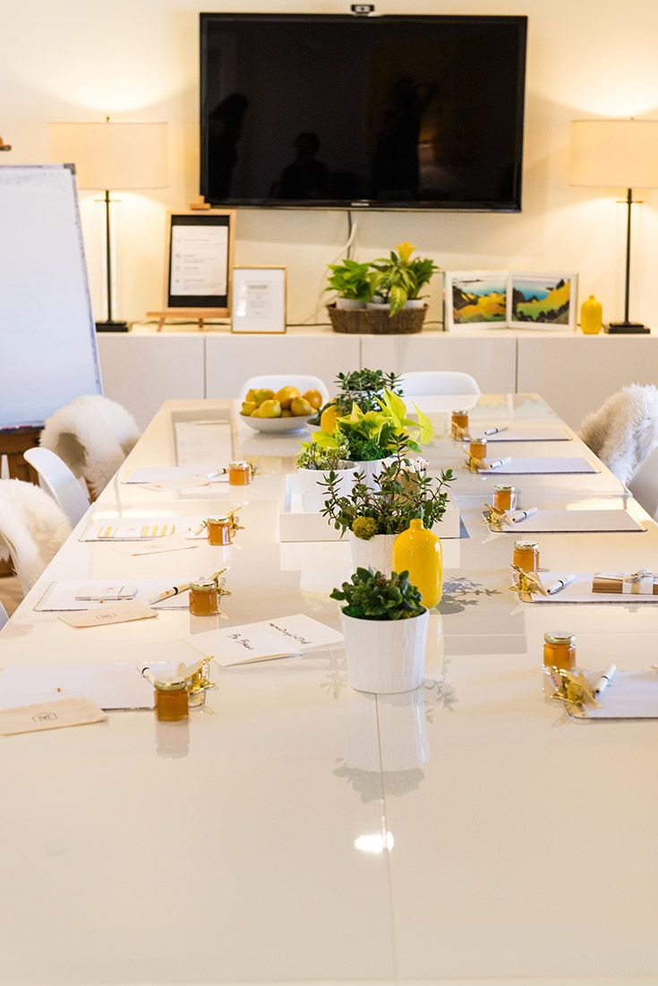 a white table with yellow flowers and place settings in front of a flat screen tv