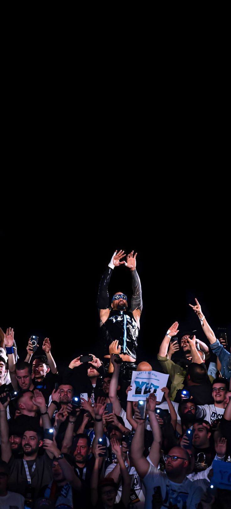 a man riding a skateboard in front of a crowd of people with their hands up