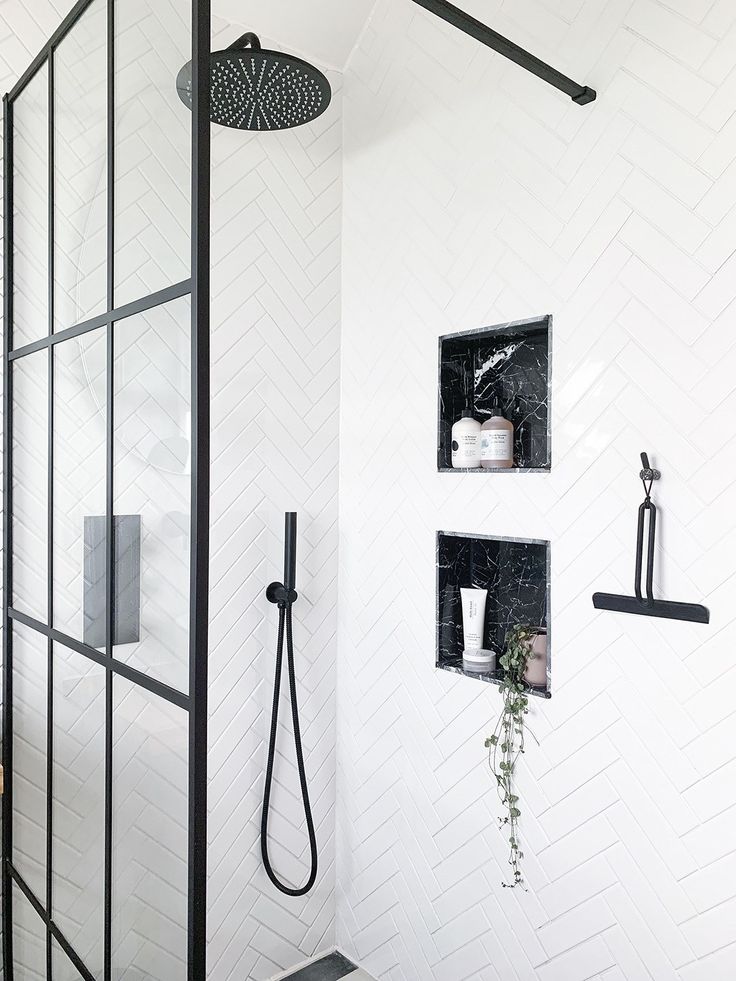 a bathroom with black fixtures and white tiles on the walls, including a shower head