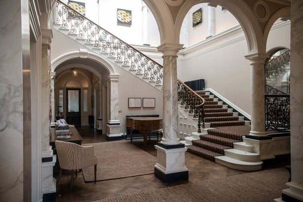 a large foyer with marble steps and chandeliers on either side of the staircase