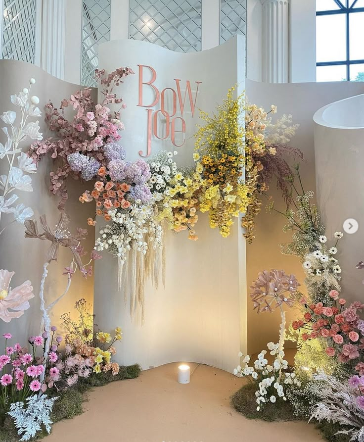 an arrangement of flowers on display in front of a wall with the words bow top