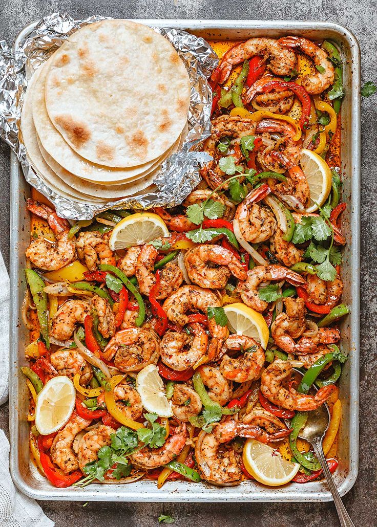 a sheet pan filled with shrimp, peppers and tortillas