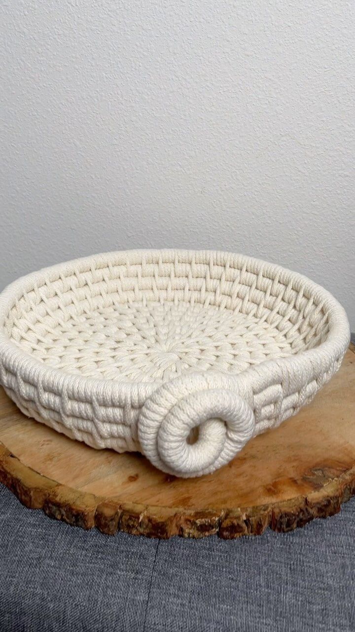 a white woven basket sitting on top of a wooden slab