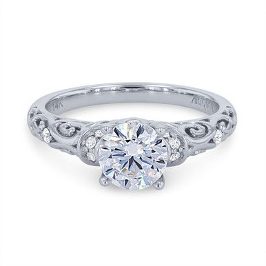 a white gold engagement ring with an intricate design and round brilliant cut diamond in the center