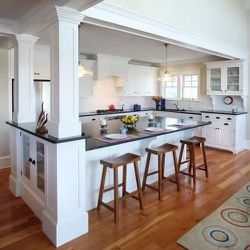 a large kitchen with white cabinets and black counter tops is pictured in this image, the island has three stools on it