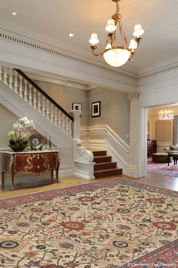 an ornately decorated foyer with chandelier and rug on the floor in front of stairs