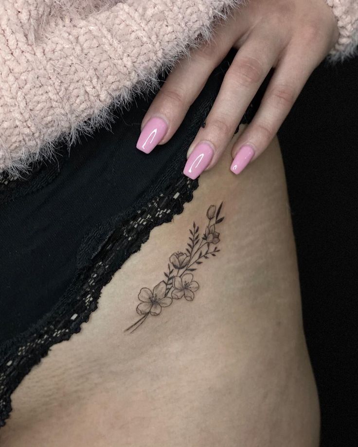 a woman's stomach with flowers on it and a tattoo on her lower side