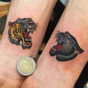 two people with tattoos on their arms and one has a tiger tattoo on the wrist