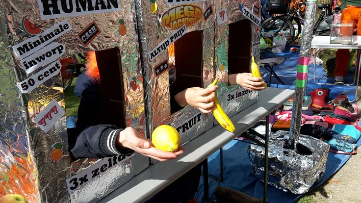 a person holding a banana in front of a fruit stand with signs on the sides