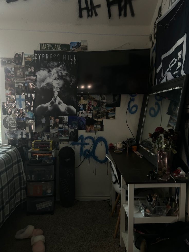 a bedroom with posters on the wall and a desk in front of it, next to a bed