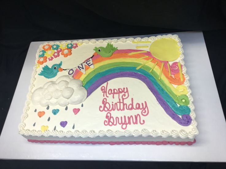 a birthday cake decorated with rainbows and clouds