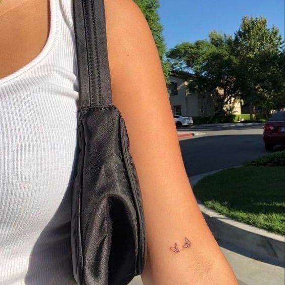 a woman's arm with a small butterfly tattoo on the left side of her arm