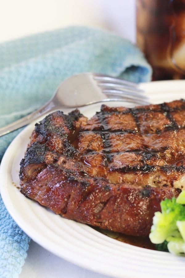 a steak and broccoli on a white plate with a fork next to it