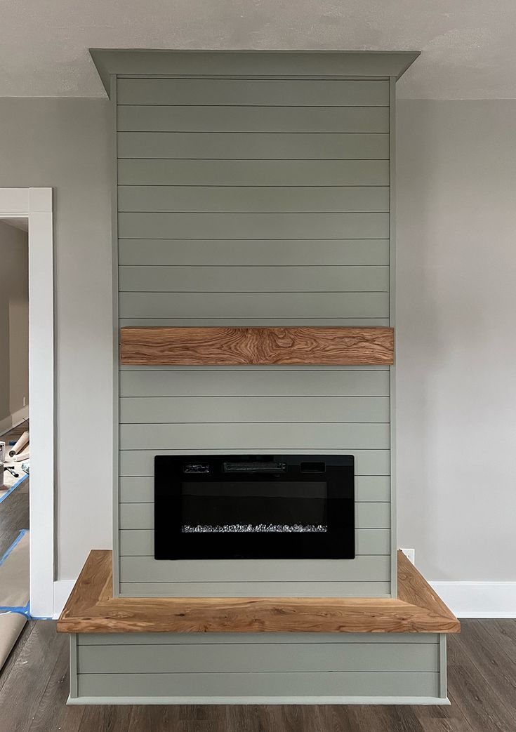 an empty room with a fireplace in the middle and wood on the bottom shelf,