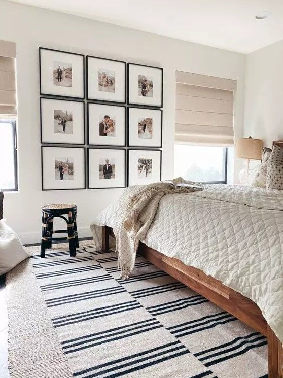 a bedroom with white walls and pictures on the wall above the bed, along with an area rug