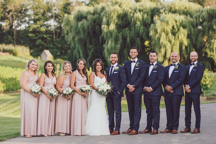 a group of people standing next to each other in front of some trees and bushes