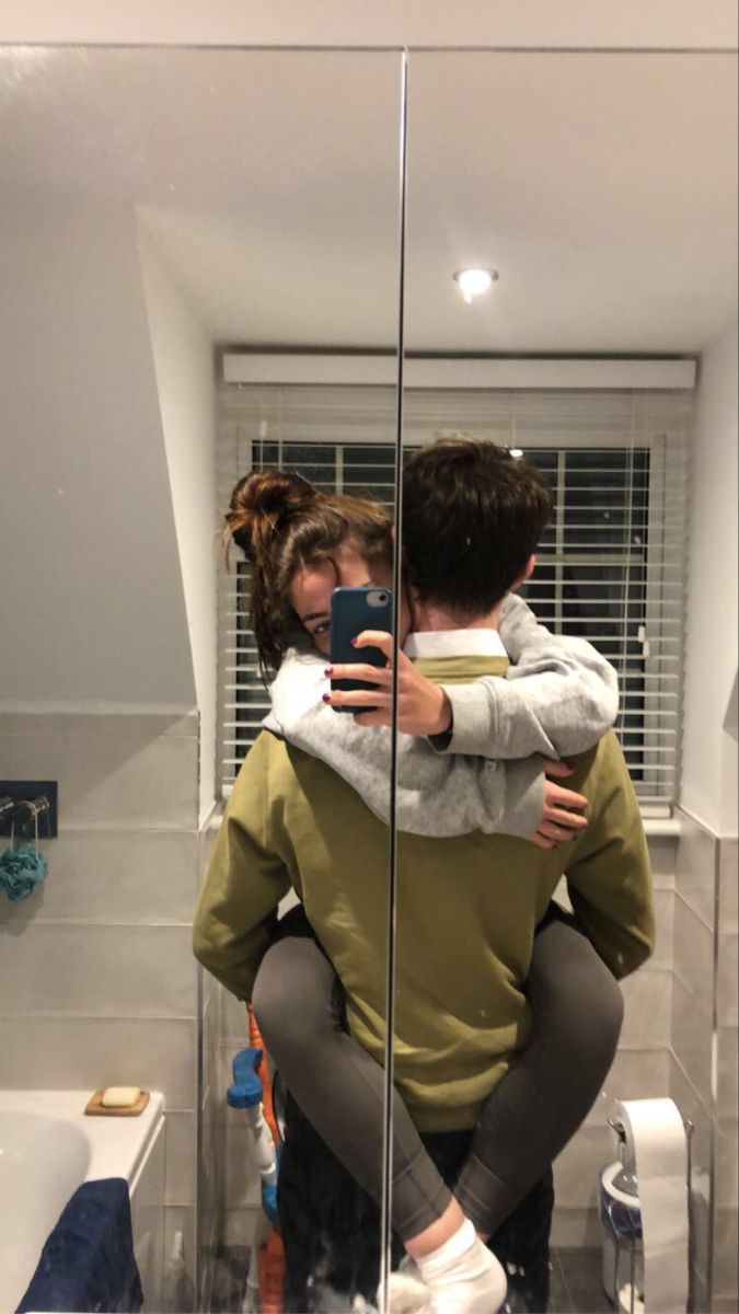 two people hugging each other in front of a mirror