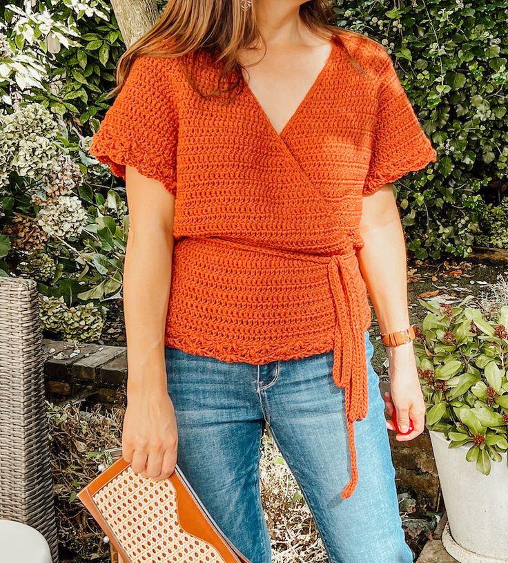 a woman in an orange top holding a purse