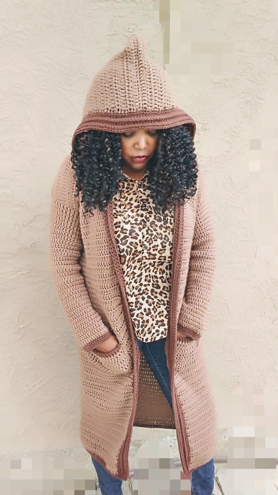 a woman standing in front of a white wall wearing a leopard print shirt and pink cardigan