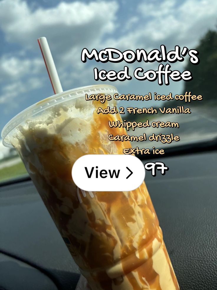 an iced coffee in a plastic cup sitting on top of a car dashboard with the caption mcdonald's iced coffee