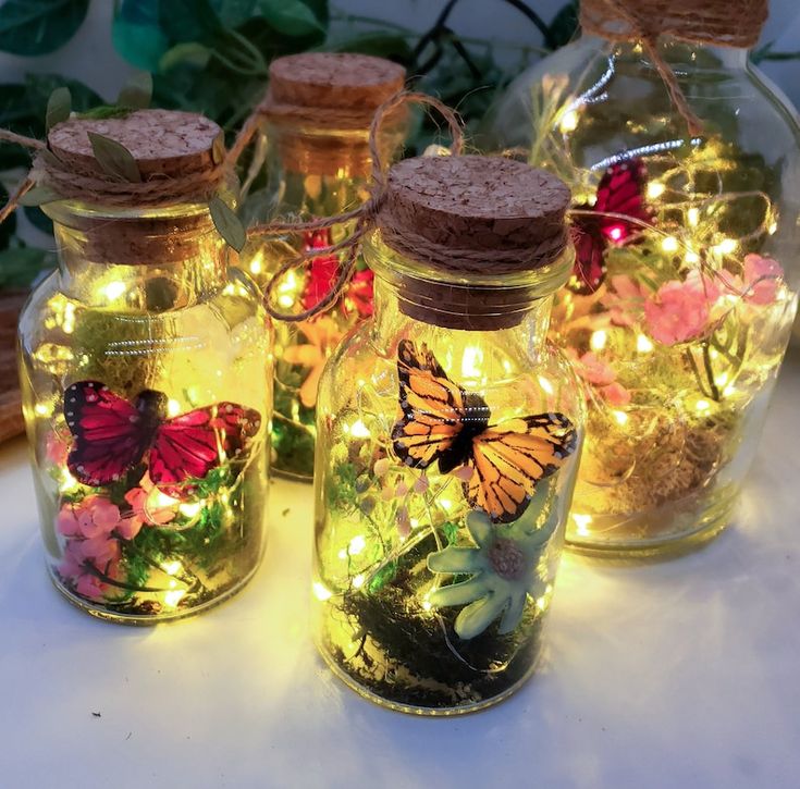 three glass jars filled with lights and butterflies