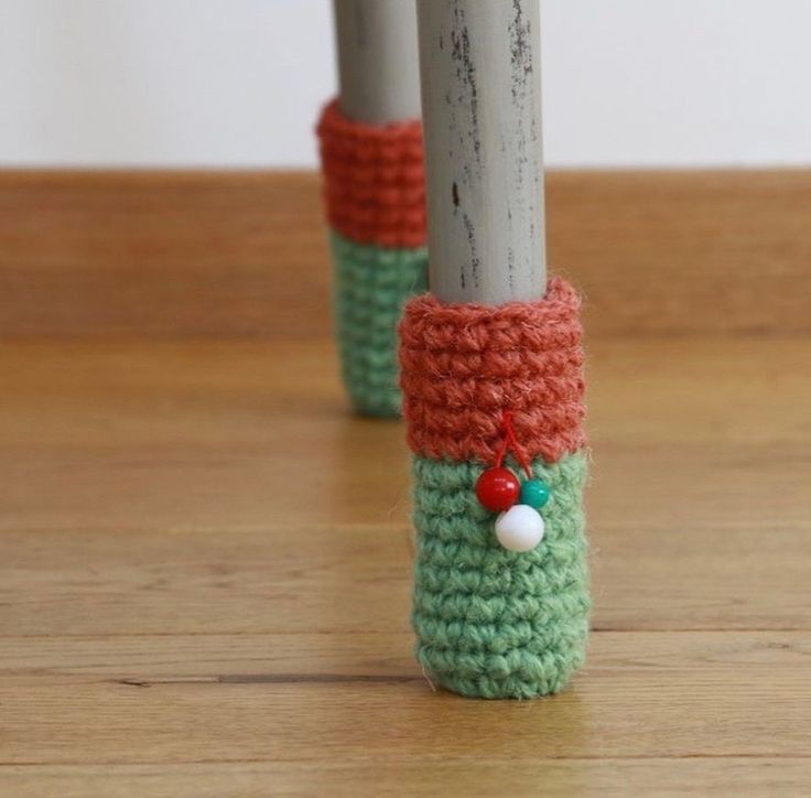 two crocheted poles with red, green and white decorations on them sitting on a wooden floor