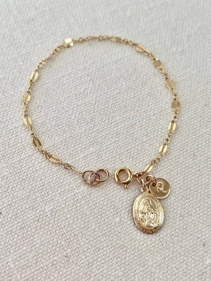 Virgin Mary bracelet, personalized bracelet, meaningful gift for yourself or the people you love. Details. - Miraculous medal 13 x 9 mm. - Sturdy chain genuine 14 k gold filled. - Disk 6.5 mm. - Elegant or script uppercase font. - All components are 14 k gold filled, quality mark. - Ethically sourced. - Your style, our design. Thank you very much for visiting my shop. Minimalist Gold Rosary Bracelet Gift, Spiritual 14k Gold Bracelet As A Gift, Dainty Personalized Charm Bracelets, Dainty Charms Bracelets For Personalized Gift, Dainty Bracelets With Charms For Personalized Gift, Dainty Oval Bracelets As Gift, Yellow Gold Rosary Bracelet As Gift, Dainty Oval Bracelets For Gifts, Dainty Oval Bracelet For Gift