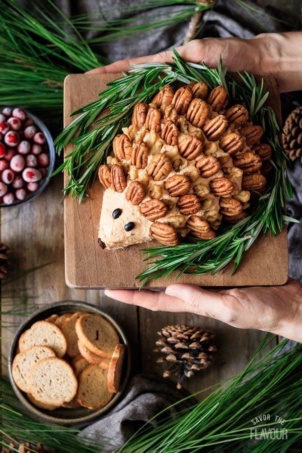 a hedge cookie on a cutting board surrounded by pine cones and nuts