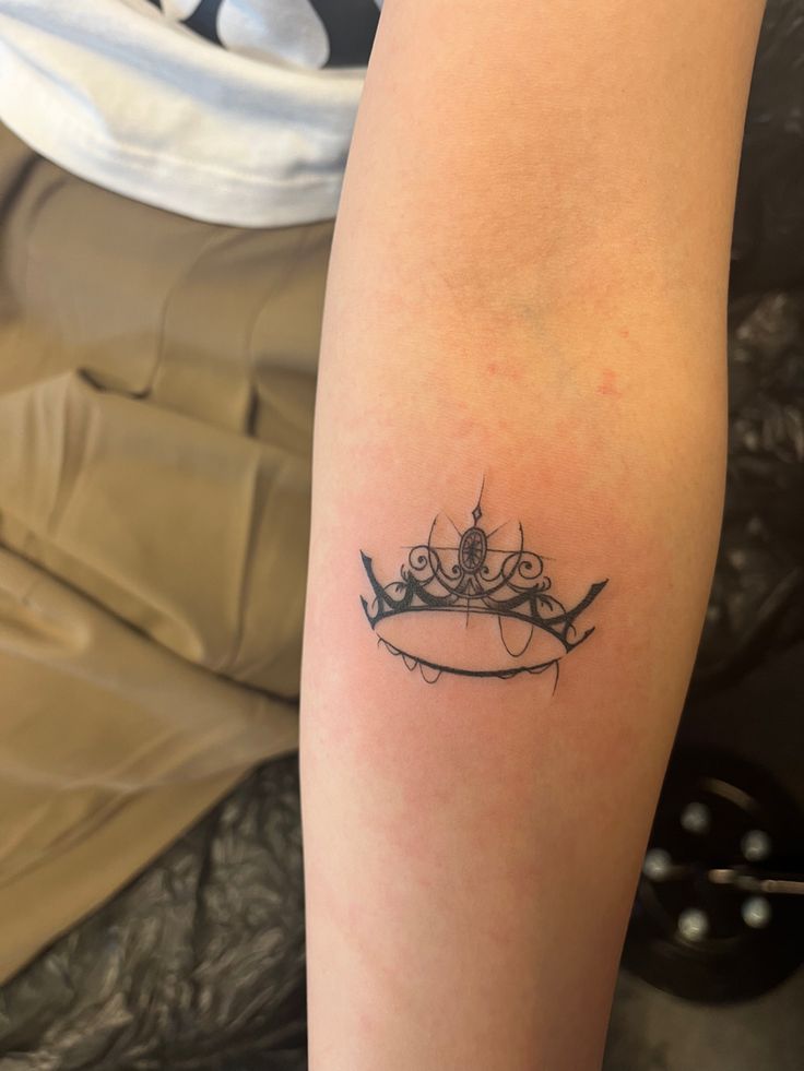 a woman's arm with a crown tattoo on it