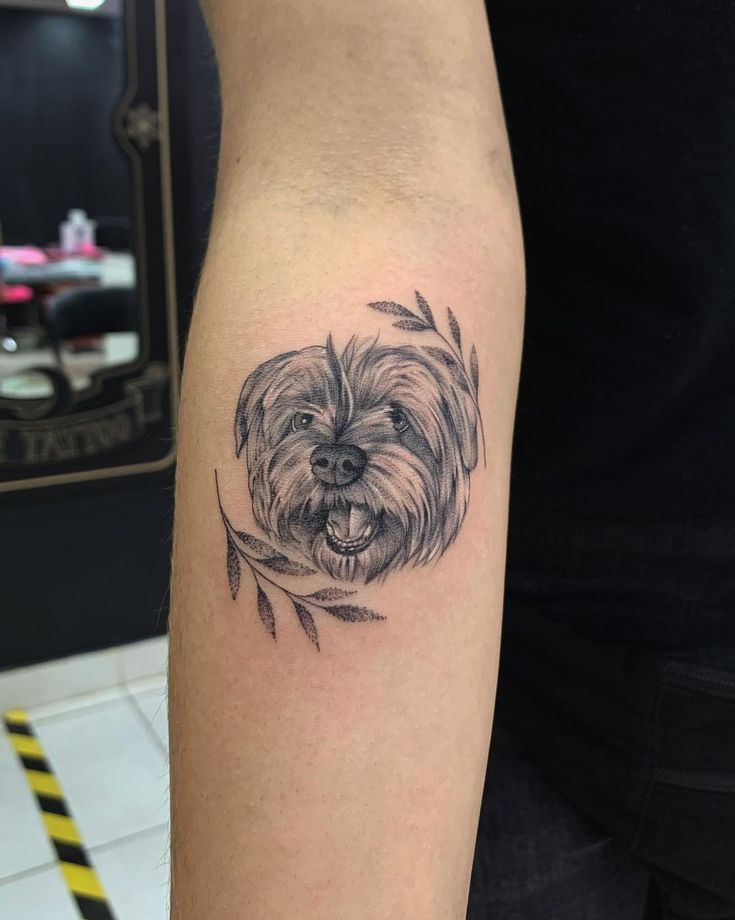 a small black and white dog tattoo on the arm