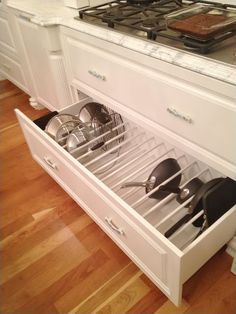 an open drawer in the middle of a kitchen with pots and pans on it