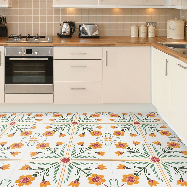 a kitchen with white cabinets and yellow flowers on the floor, next to a stove top oven