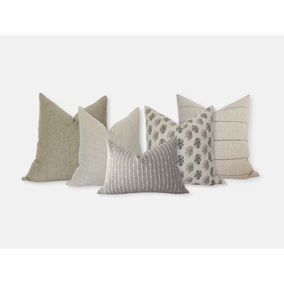 four pillows in different colors and patterns on a white background, one is grey the other is beige