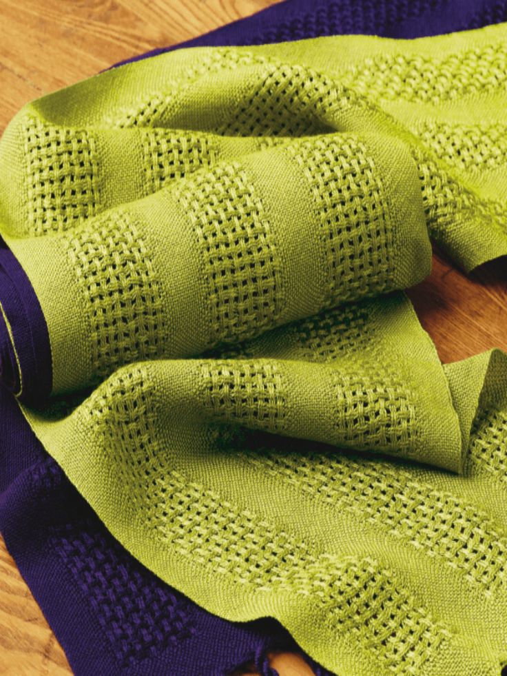 a pair of green socks sitting on top of a wooden floor next to a purple towel