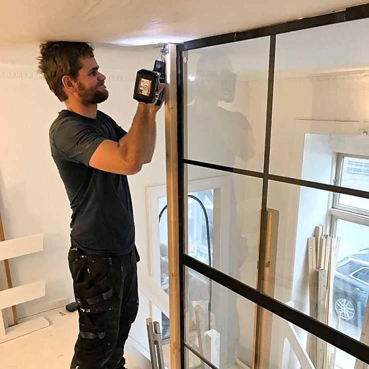 a man holding up a camera in front of a glass door that is being installed