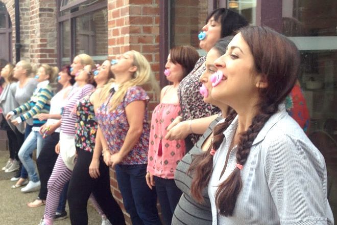 a group of women standing next to each other in front of a brick building with their mouths open