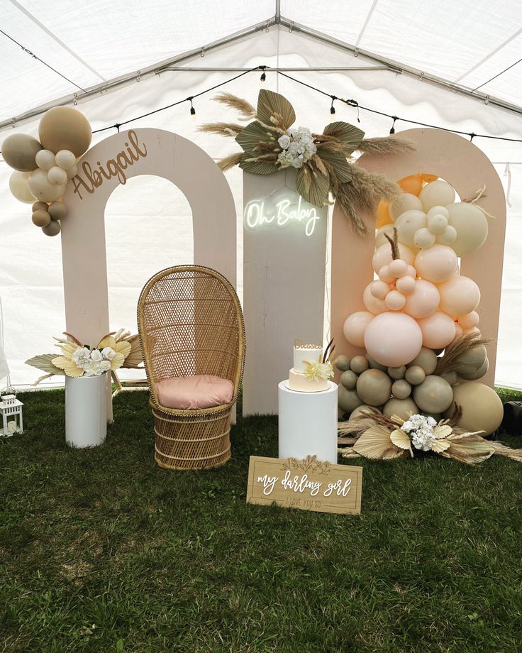 an outdoor event with balloons and decorations on the grass under a white tented area