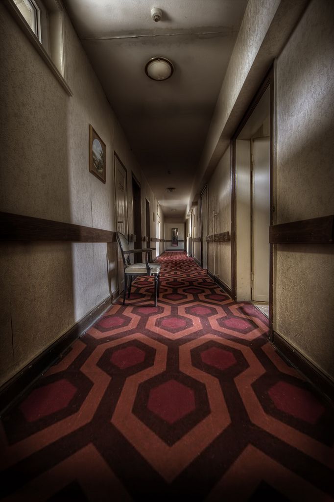 an empty hallway with red carpet and chairs