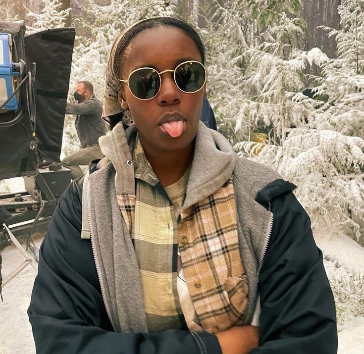 a woman sticking her tongue out in front of a camera set up on a snowy mountain