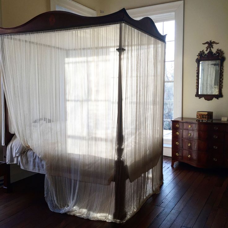 a canopy bed with sheer curtains in a bedroom