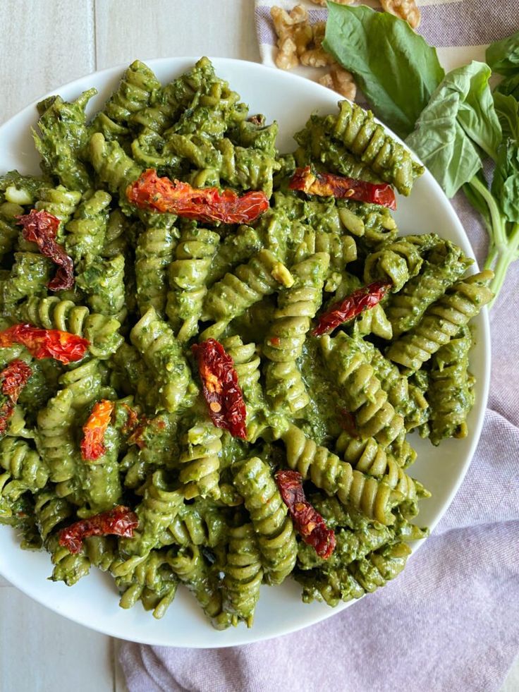 a white plate topped with pasta covered in pesto