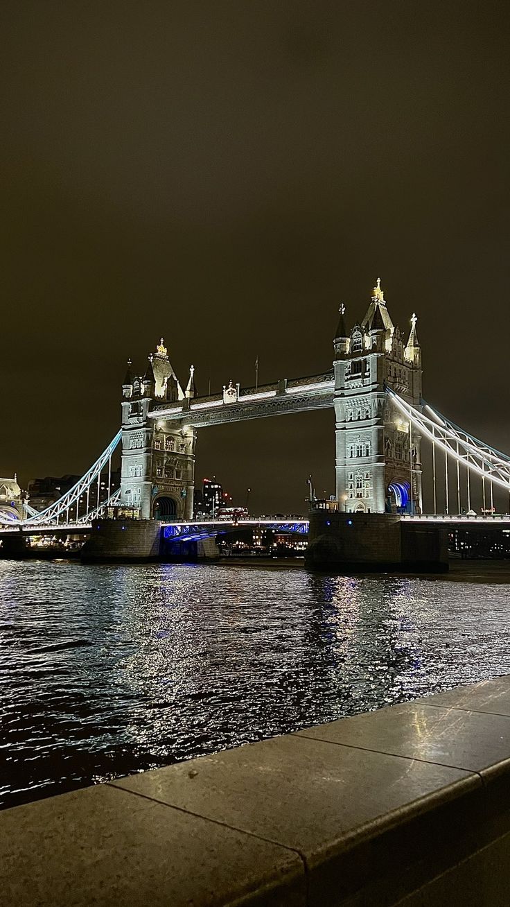 the tower bridge is lit up at night