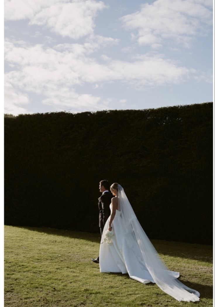 a bride and groom standing in the grass