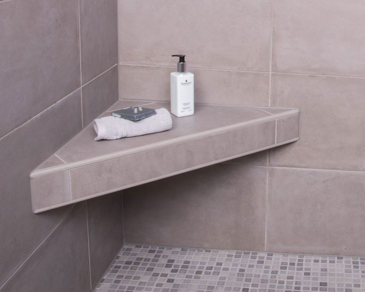 a shelf in the corner of a tiled bathroom